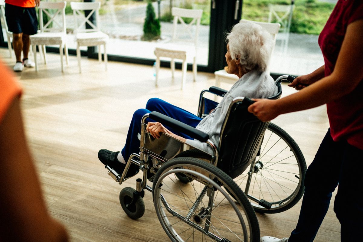 Adulta mayor disfrutando de una terraza luminosa junto a su cuidadora